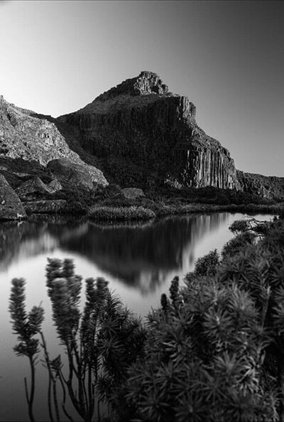 Black and white photo looking across a lake at some mountains.